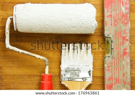 Painting tools stained in white paint on the background of wooden boards