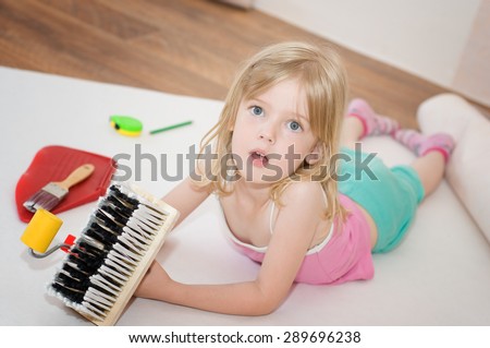 Little girl with paint brush. Apartment repair. Wallpapering. Stock Photo