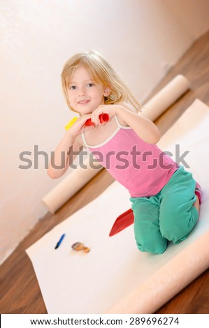 Little girl with paint roller. Apartment repair. Wallpapering. Stock Photo
