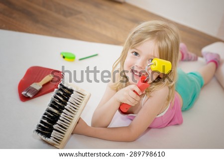 Little girl with paint brush and roller. Apartment repair. Wallpapering. Stock Photo