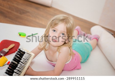 Little girl with paint brush. Apartment repair. Wallpapering. Stock Photo