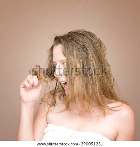 Young woman looks at her hair. Hair problems. Stock photo.