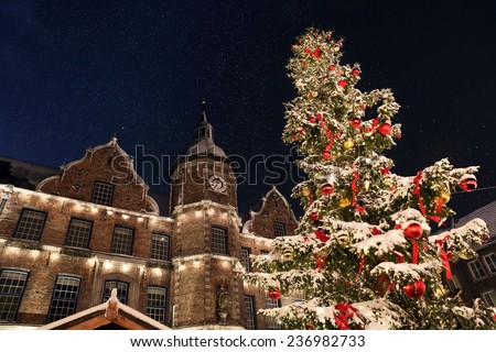 Spectacular view on the DÃ?Â¼sseldorf town hall and Marktplatz Christmas market with a snowcapped Christmas tree. The picture was taken during light snowfall with a sensational night sky.