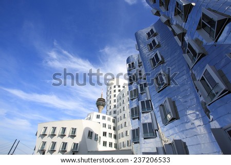 DUSSELDORF, GERMANY - SEPTEMBER 28, 2014: Frank O. Gehry\'s distorted buildings in the media harbor district with the Rheinturm tower as a backdrop on September 28, 2014 in Dusseldorf.