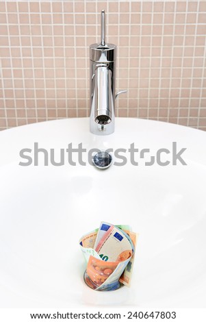 Euro banknotes in sink expressing the idiom \'pouring money down the drain\'
