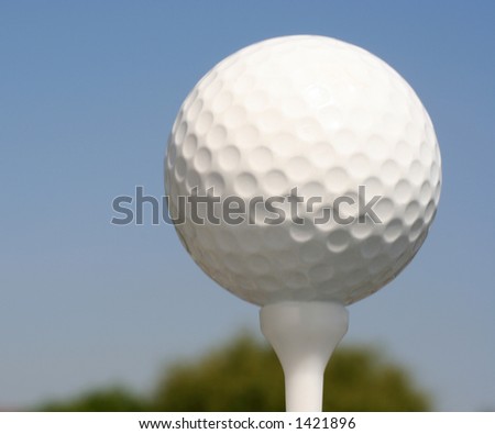 Golfball on white tee against blue sky
