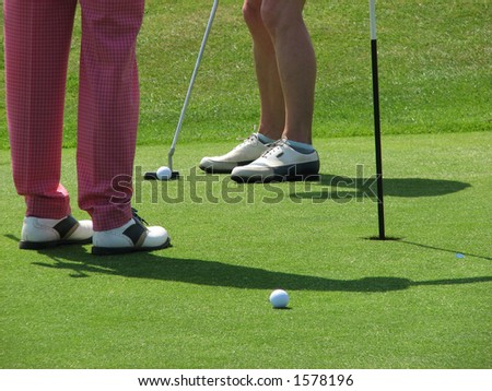 Woman lines up hole on golf green.