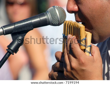 Male street musician entertaining crowd by playing pipes
