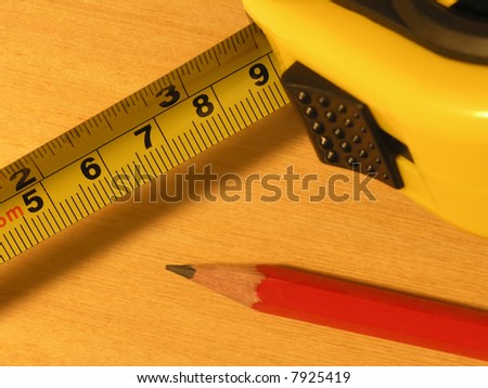 Close-up of tape measure and pencil on wooden surface