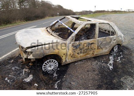 stock photo Burnt out abandoned car on side of road
