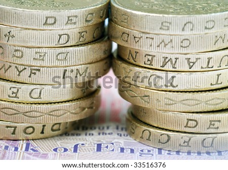 Close-up of stack of UK pound coins on bank note