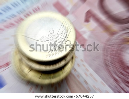 Euro coins resting on banknotes with zoom effect