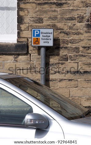 Disabled badge holders parking sign behind parked car.