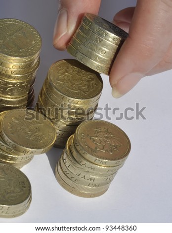 Closeup of stacks of pound coins with hand holding coins.