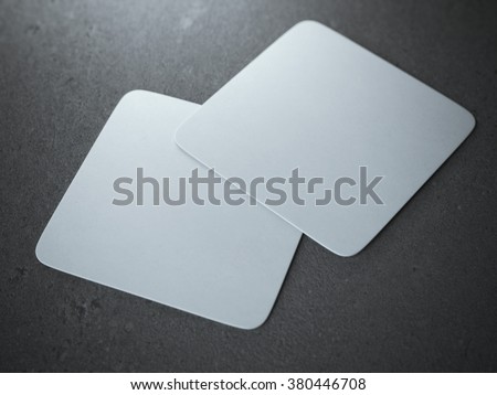 Two white square beer coasters