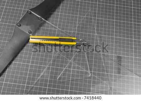 square, t-rule and yellow cutter knife on black and white
