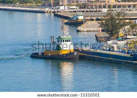 blue and green tugboat leave caribbean dock