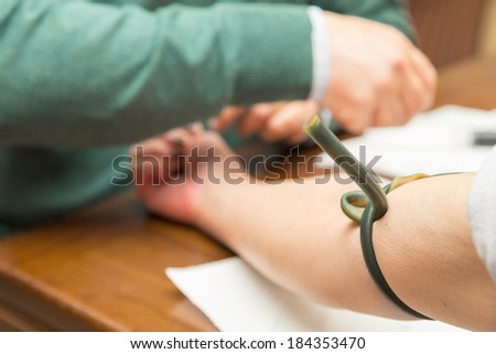 A doctor/nurse on call has just tied a tourniquet to a female patient in order to injecting a dietary iron medicine