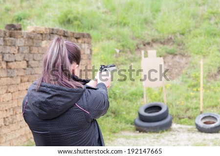 Civilian girl is practicing with her 9mm gun in a shooting range for improving her self-defense technique with gun