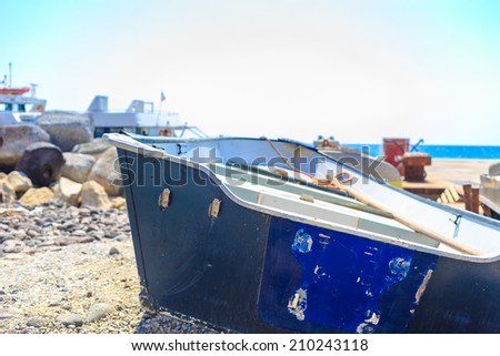 The back of a fishing boat abandoned and ruined. The boat is surrounded by a beautiful mediterranean seascape