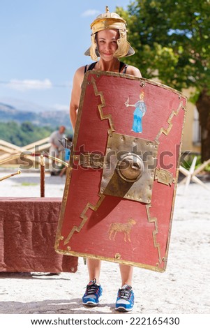 Girl wearing typical helmet and holding a shield used by the Roman legions of the Roman Empire.