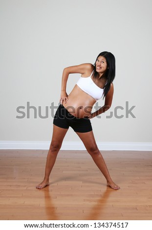 Pregnant Peruvian woman exercising in a room