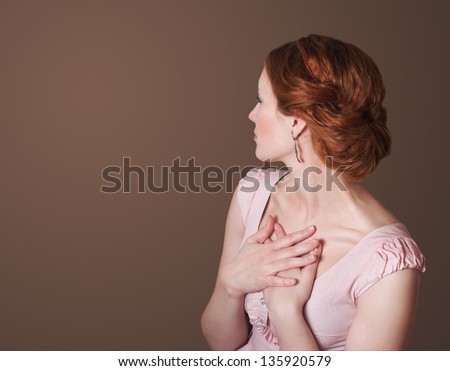 Attractive red hair woman in a pink dress with arms crossed on his chest turned back