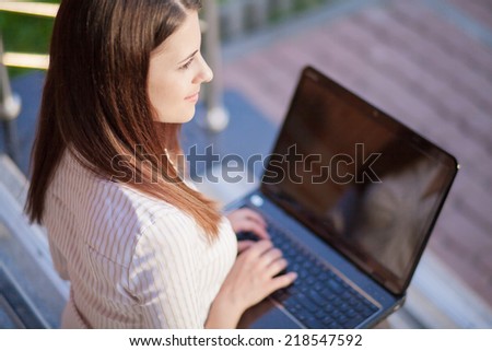 A young pretty business woman outside office building with laptop computer