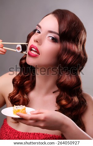 Young woman eating sushi with a chopsticks