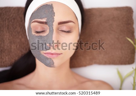 Spa Woman applying Facial cleansing Mask. Beauty Treatments