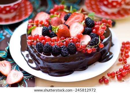 Heart shaped chocolate cake with chocolate ganashe decorated with fresh strawberries, red currant and blackberries