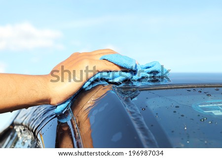 cleaning black car by hand blue sky background