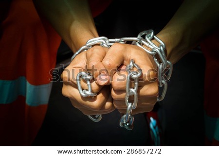 Dramatic detail of the chained hands of an adult man