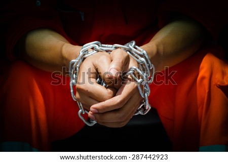 Dramatic detail of the chained hands of an adult man