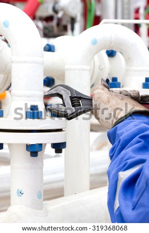 Close-up image of human hand fixing and stop leak flange by wrench in oil and gas process