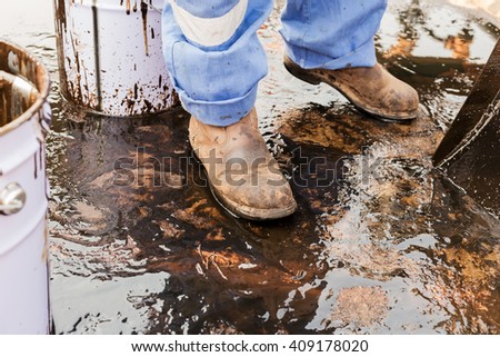 close up safety boot. worker cleaning crude oil contaminated on floor. waste management
