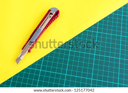 Box Cutter Knife Cutting yellow paper on cutting mat