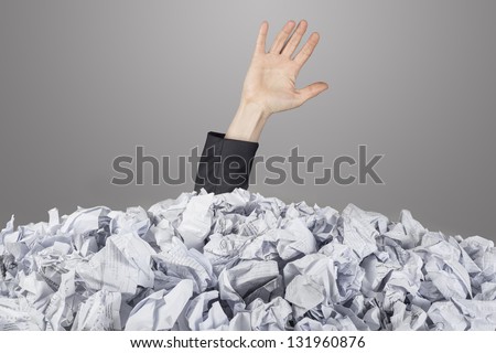 The hand reaches out from big heap of crumpled papers