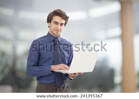 Portrait of young businessman holding laptop