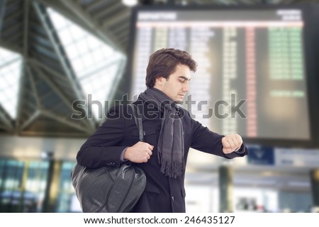 Young man looking at watch at airport