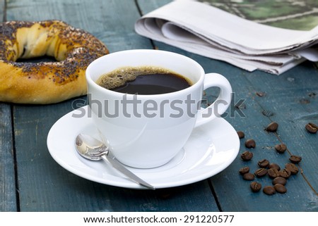 Cup of coffee with bagel and newspaper