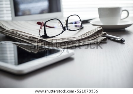 Newspaper with tablet on table