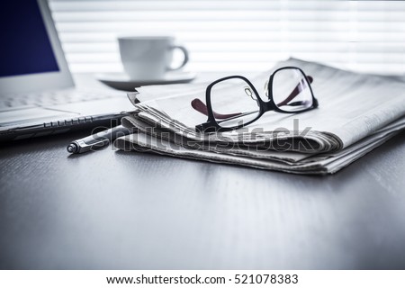 Newspaper with computer on table