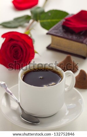 A Cup of coffee with a book and a rose.