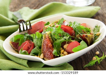 Light salad with figs, bacon, arugula and pine nuts. Selective focus.