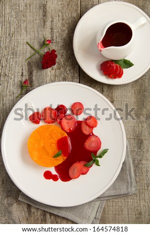 Orange terrine with strawberry sauce and strawberries.