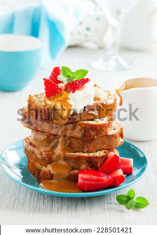 Dessert of banana cake with caramel sauce and strawberries.