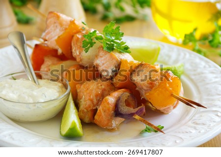Shashlik of salmon with vegetables and white sauce.