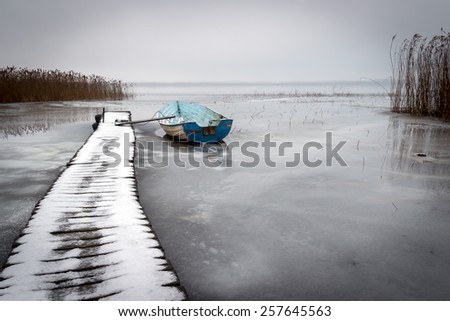 Old boat in a frozen lake winter