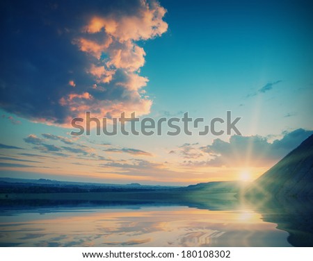 Vintage picture. Cloudy sunset in a field with a beautiful red clouds, reflected in water